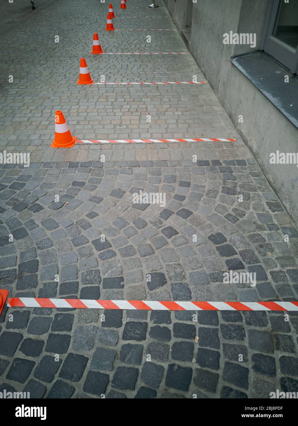 Six feet distance markings with barrier tape and traffic cones in front