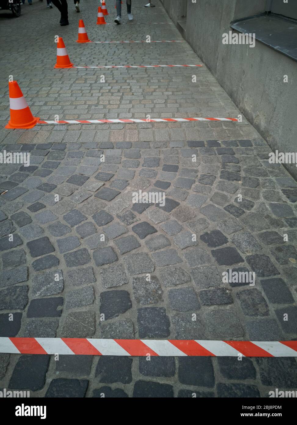 Six feet distance markings with barrier tape and traffic cones in front