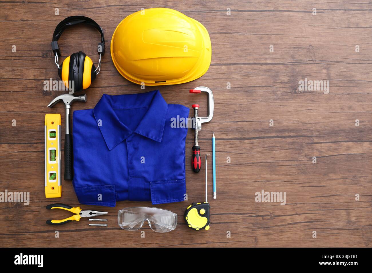 Uniform and construction tools on wooden table, top view Stock Photo