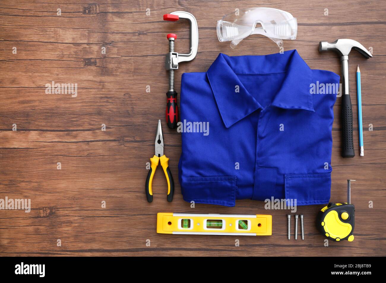 Uniform and construction tools on wooden table, top view Stock Photo