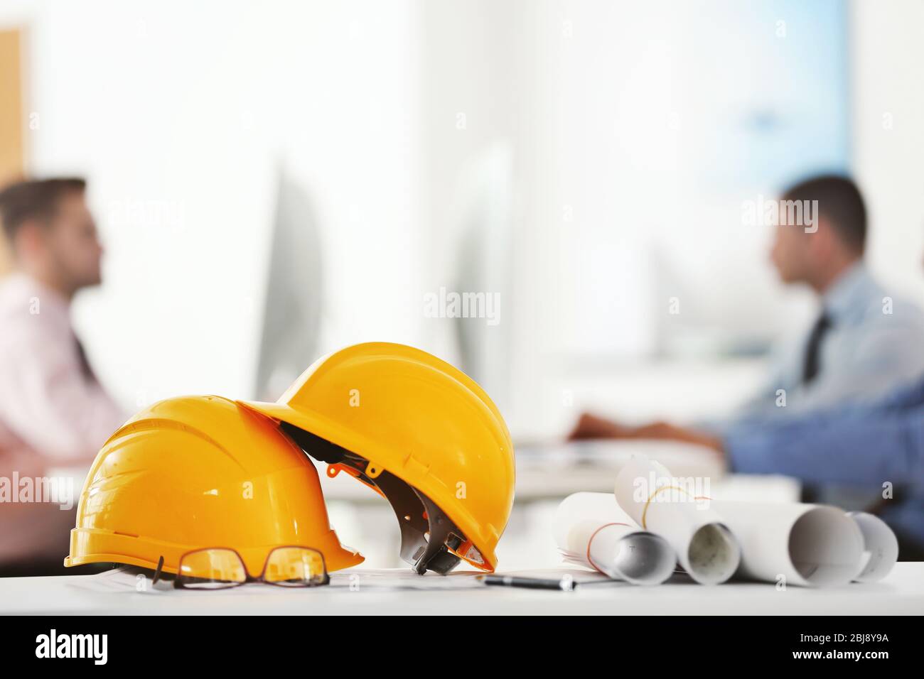 Yellow helmets on office table on blurred background Stock Photo