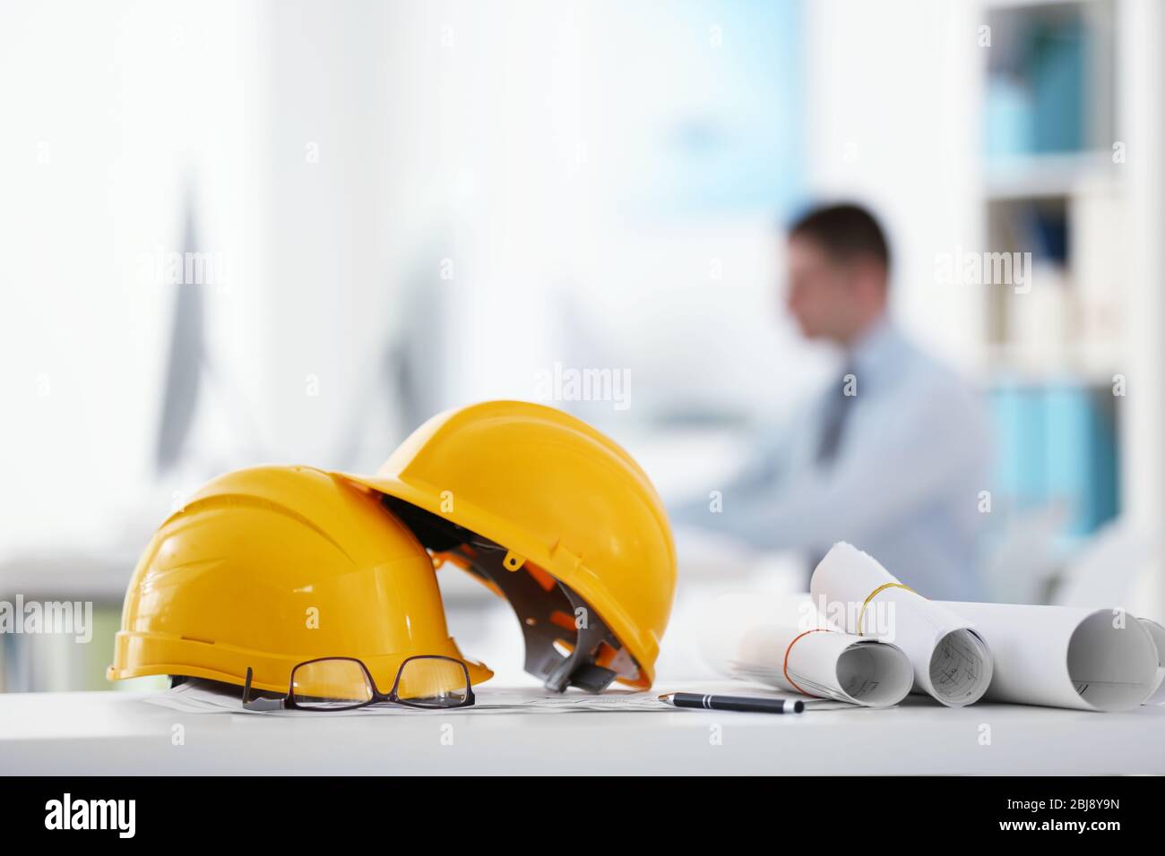 Yellow helmets on office table on blurred background Stock Photo