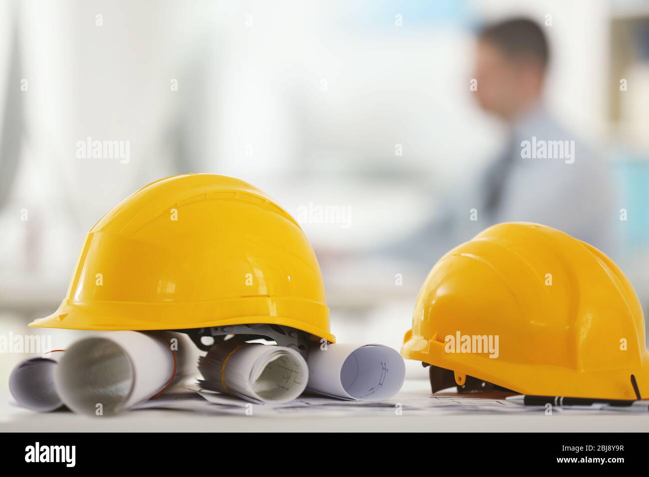 Yellow helmets on office table on blurred background Stock Photo