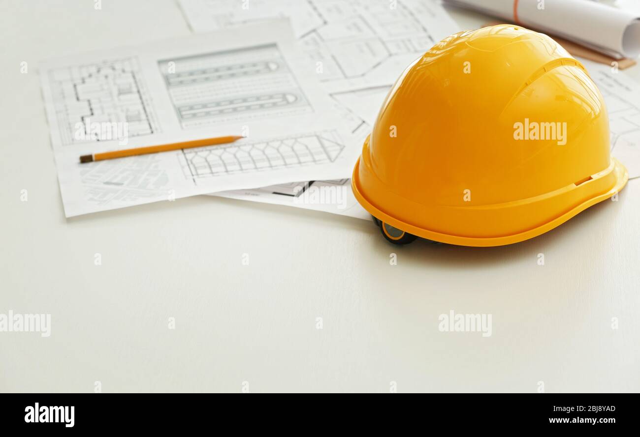 Yellow helmet on the table with blueprints Stock Photo - Alamy