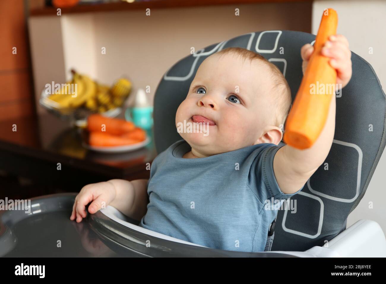 Baby holding carrot in a chair Stock Photo Alamy