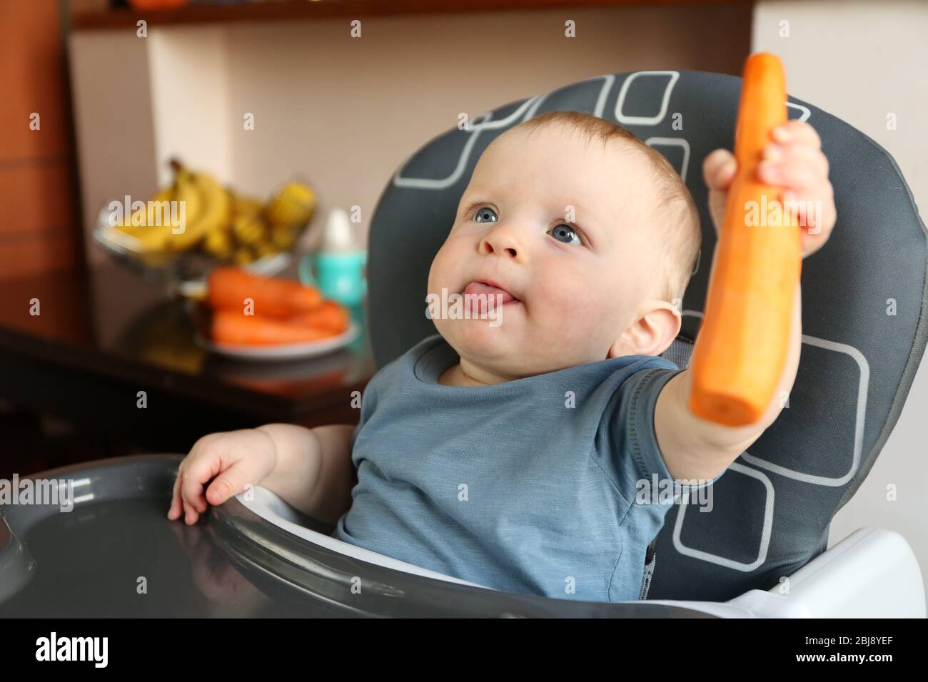 Baby holding carrot in a chair Stock Photo Alamy