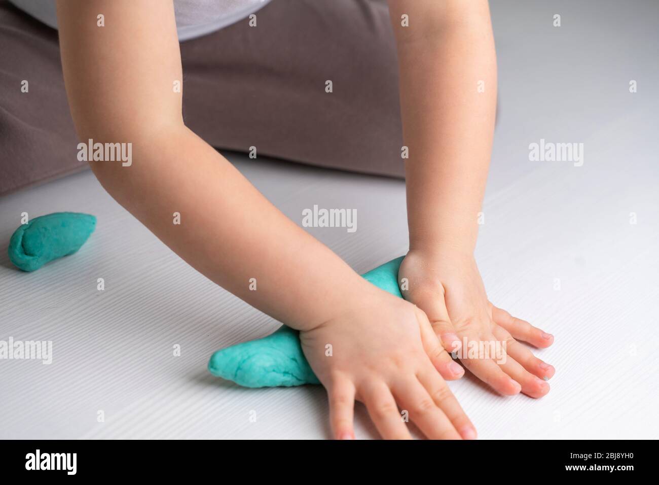 closeup hands of a preschooler child knead turquoise mass for modeling ...