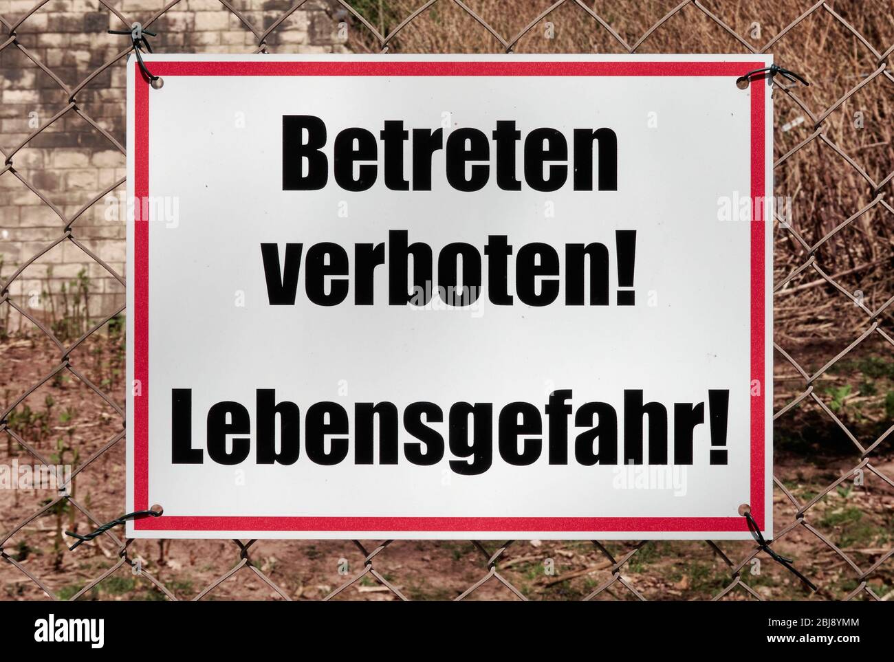 White shield with red frame and the inscription Do not enter! Danger to life! in German language Stock Photo