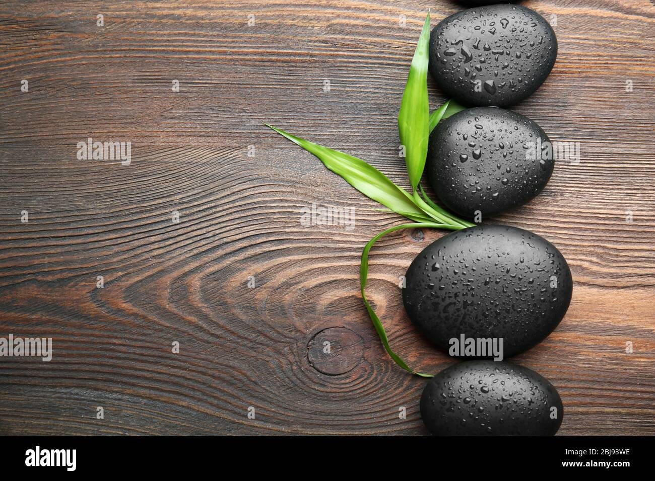 Heap of spa hot stones on wooden background Stock Photo - Alamy
