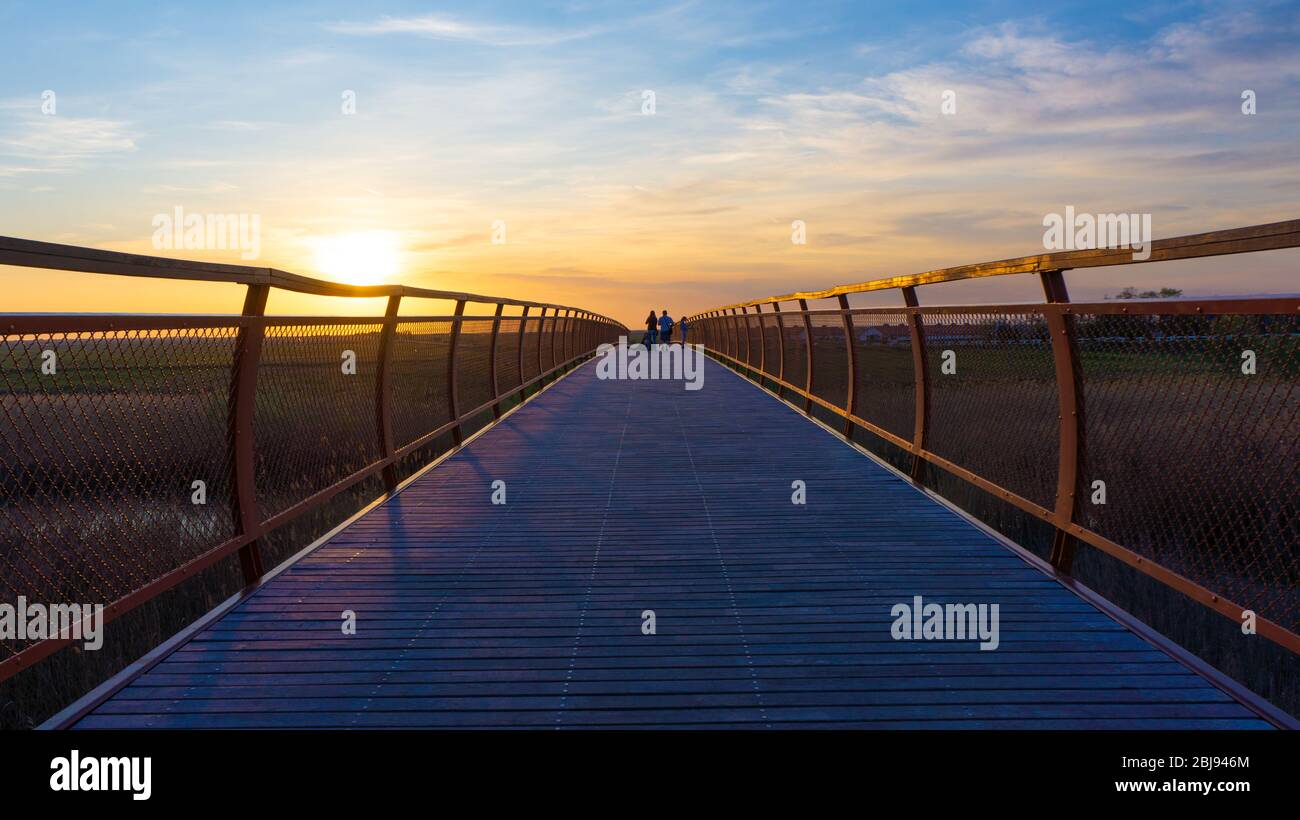 Hortobagy Hungary 04 20 2019: Tourists take photos on the wooden bridge at beautiful sunset. Stock Photo