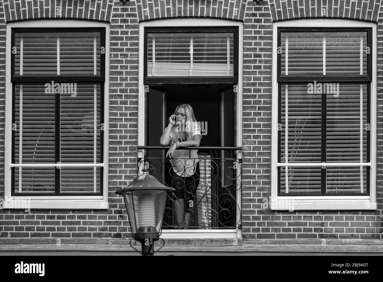 Woman speaking on the phone by French balconette in Amsterdam, Netherlands Stock Photo