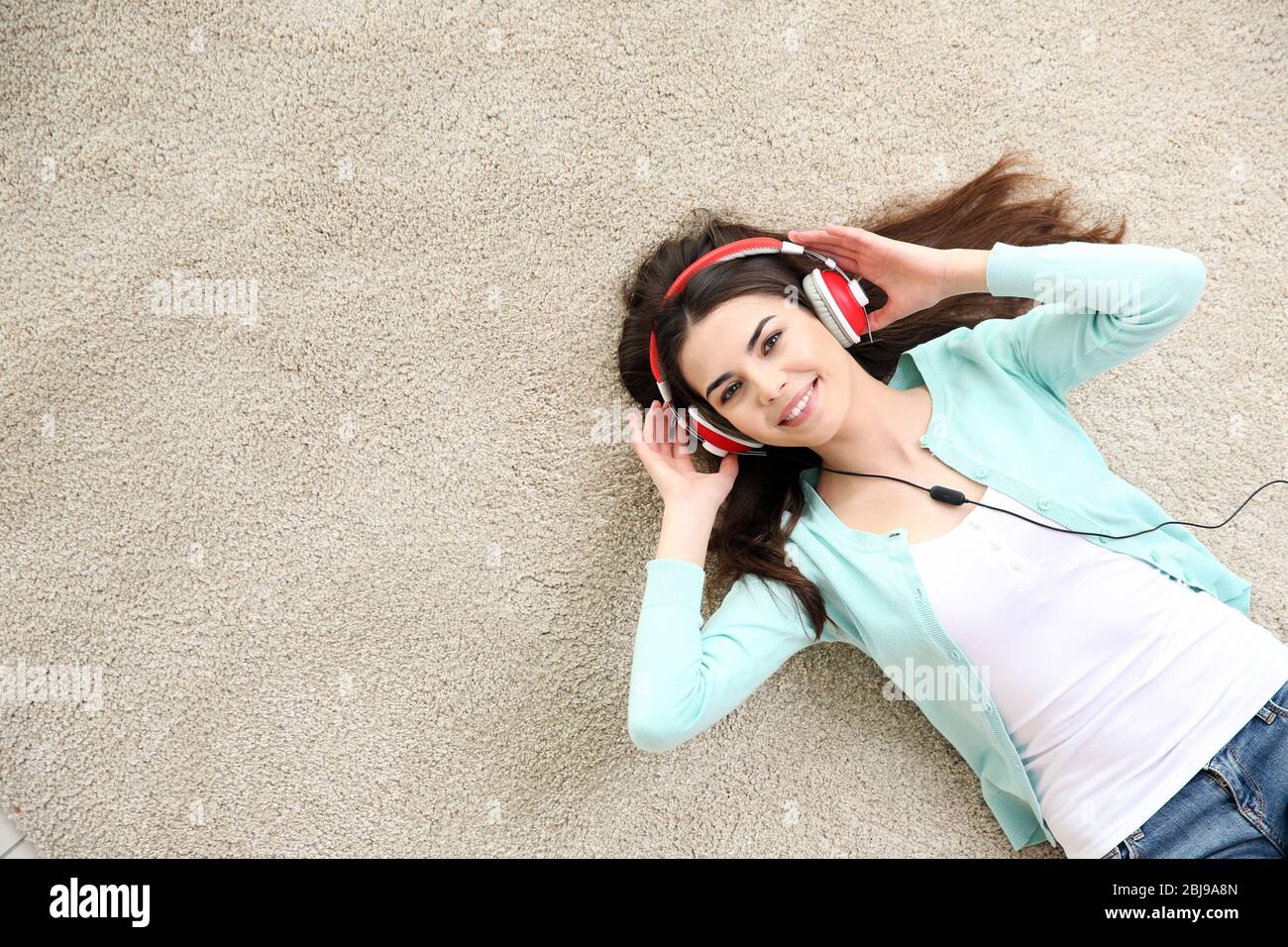 Beautiful girl with headphones lying on floor Stock Photo - Alamy