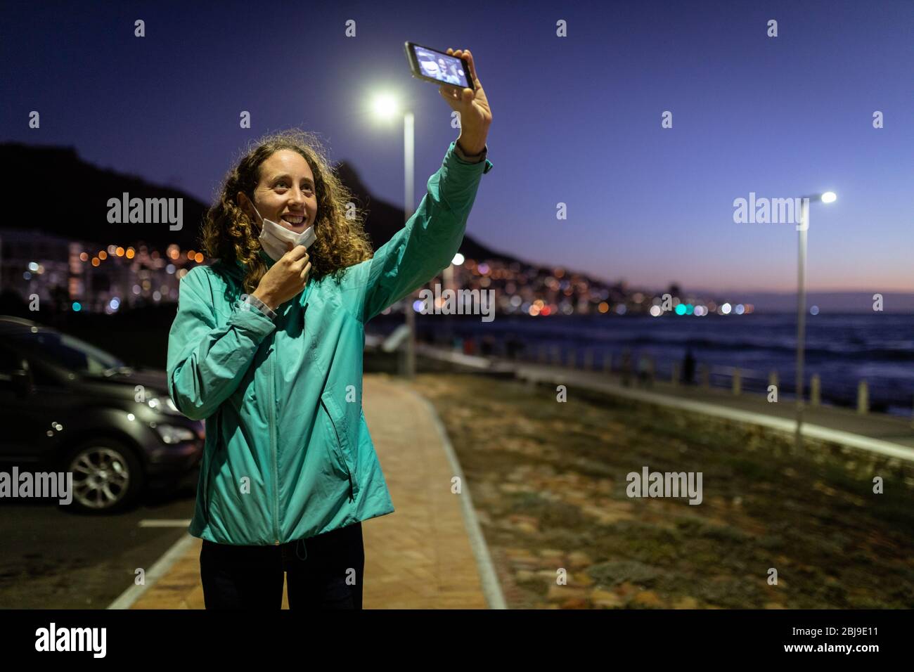 Caucasian woman putting off a protective mask, taking a picture in the streets Stock Photo