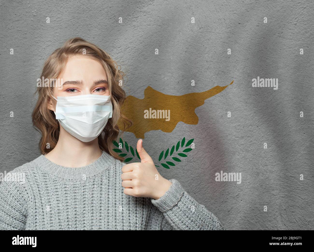 Happy woman in face mask holding thumb up on Cyprus flag background