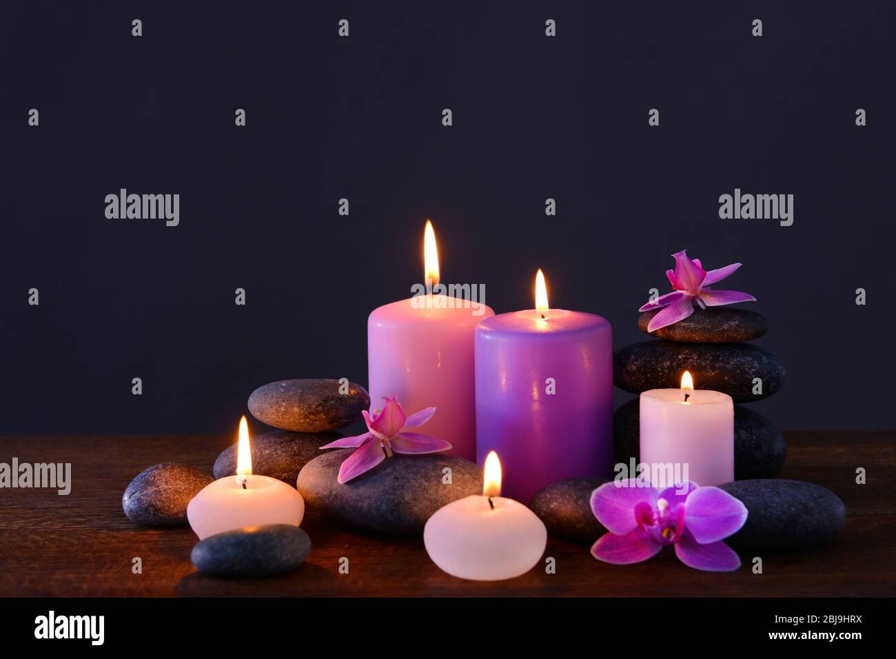 Spa stones with burning candles and flowers on grey background Stock ...