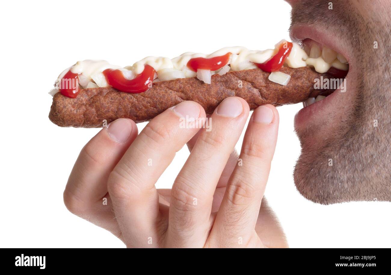 Man eating a frikadel with ketchup, mayonnaise on chopped onions, a Dutch fast food snack called 'frikadel speciaal' Stock Photo