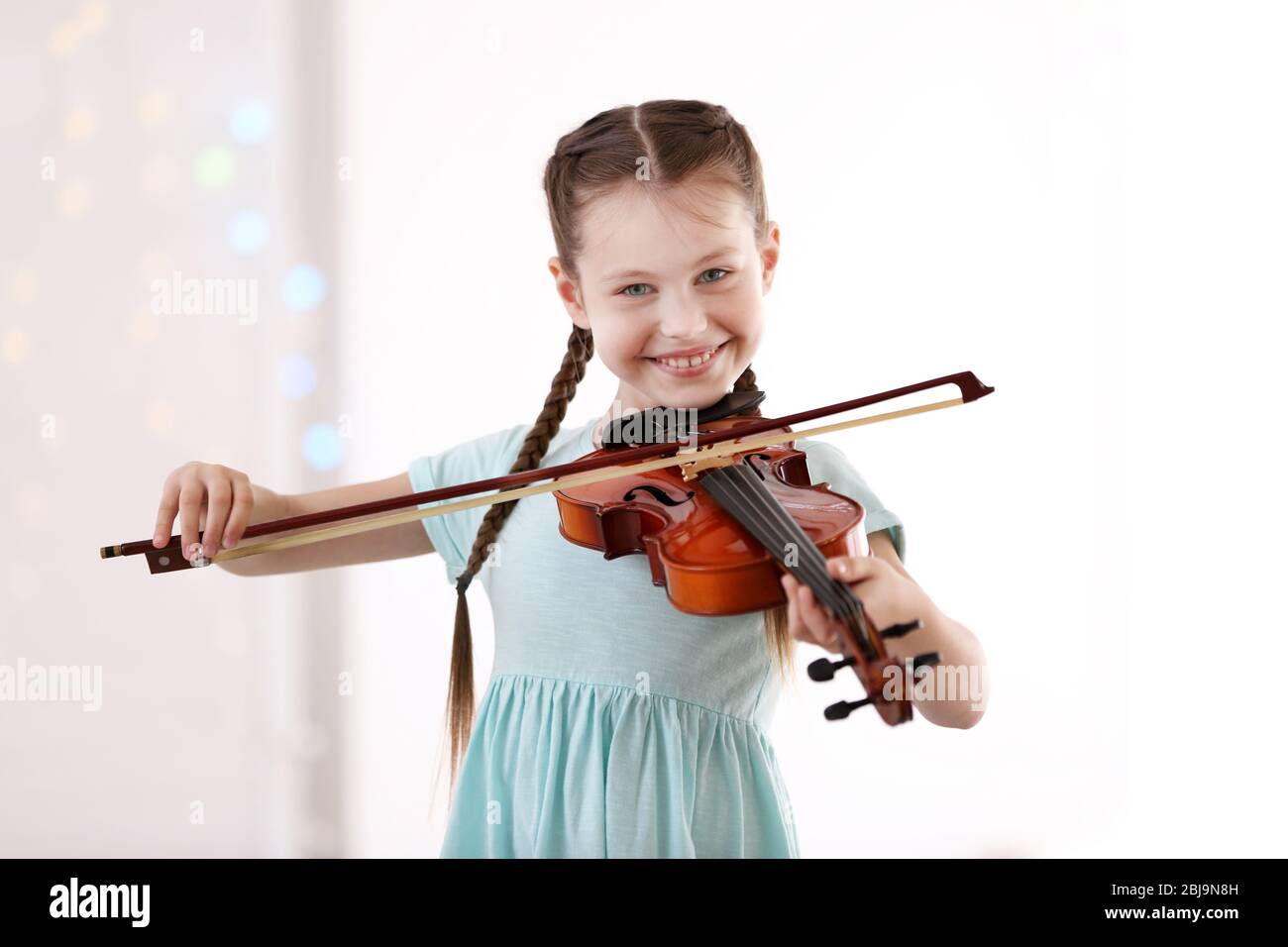 Little girl playing violin on light background Stock Photo - Alamy