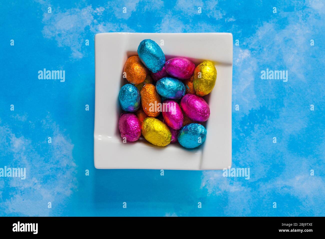 solid milk chocolate mini Easter eggs foil wrapped in bowl on blue