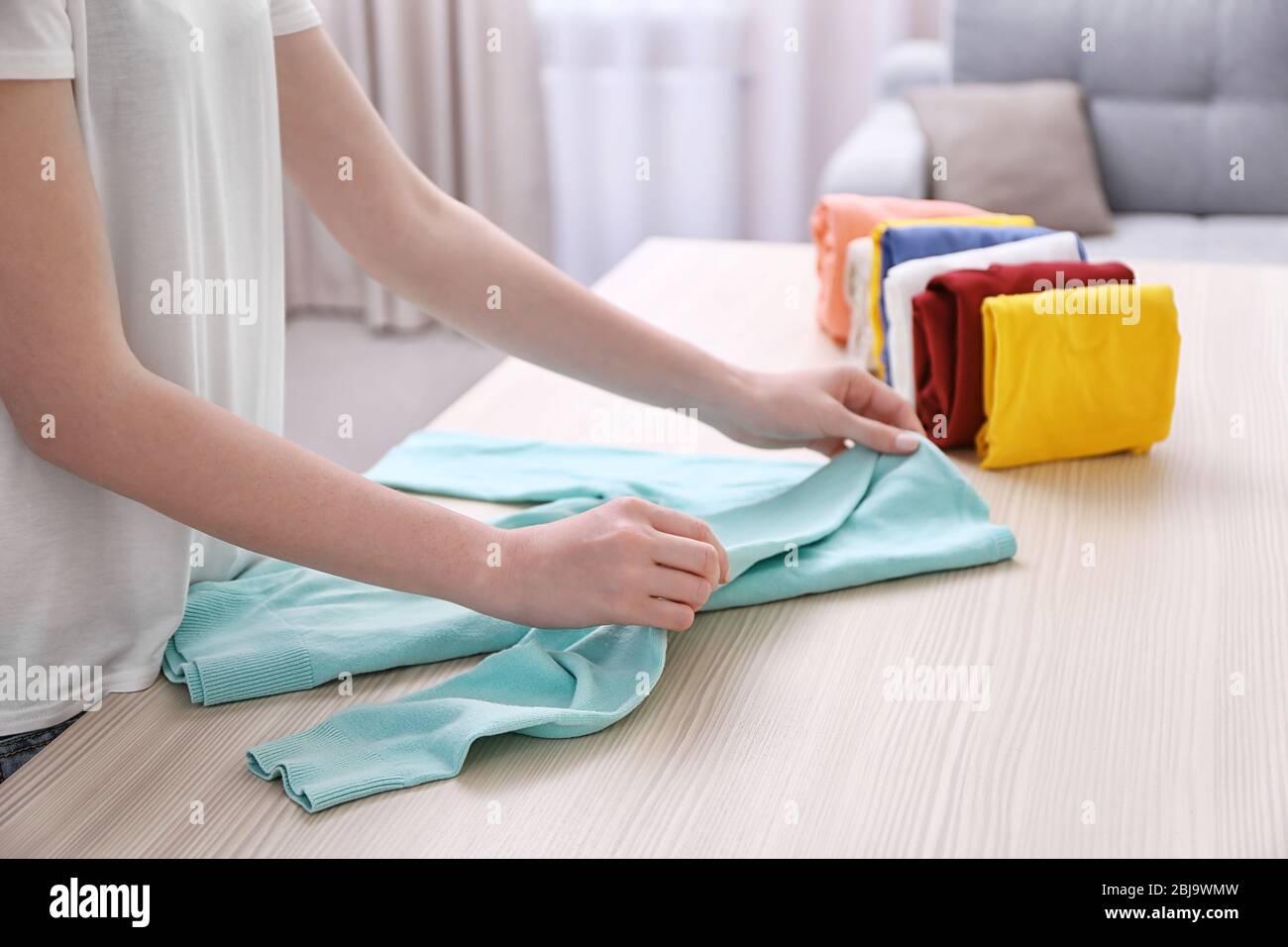 Woman folding clothes on table Stock Photo - Alamy