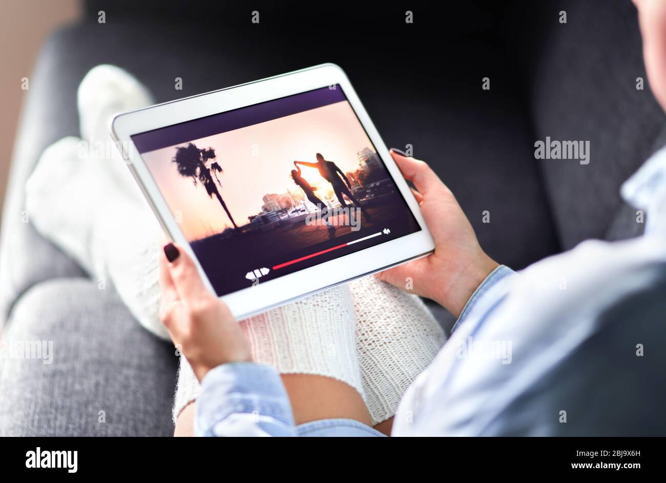Streaming movie with VOD service. Woman watching online tv series stream. Video on demand app in tablet screen. Television program or film. Stock Photo