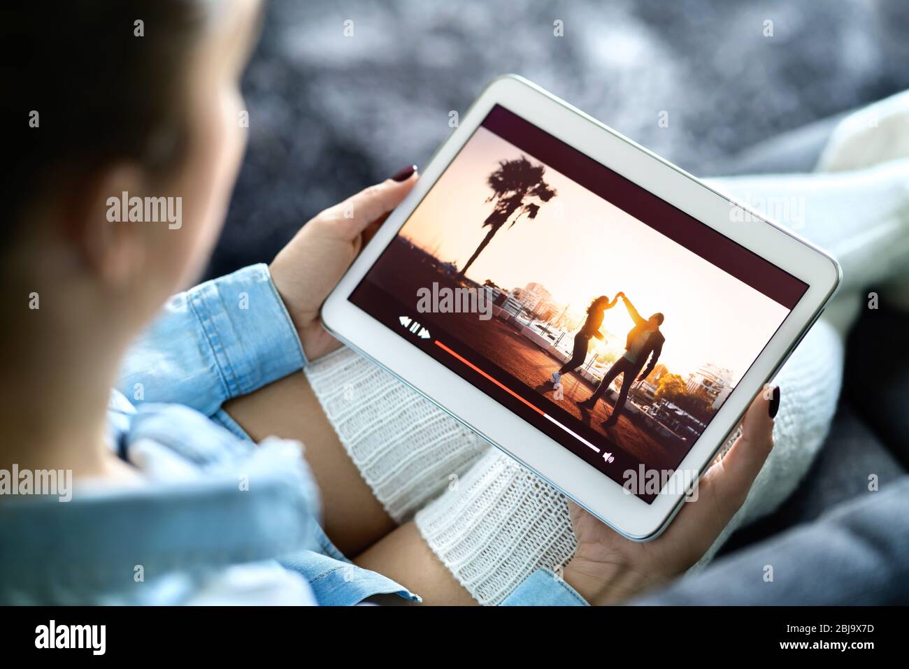 Watching movie with online stream service. Woman streaming tv series and film entertainment with tablet in the cozy comfort of home. Video on demand. Stock Photo