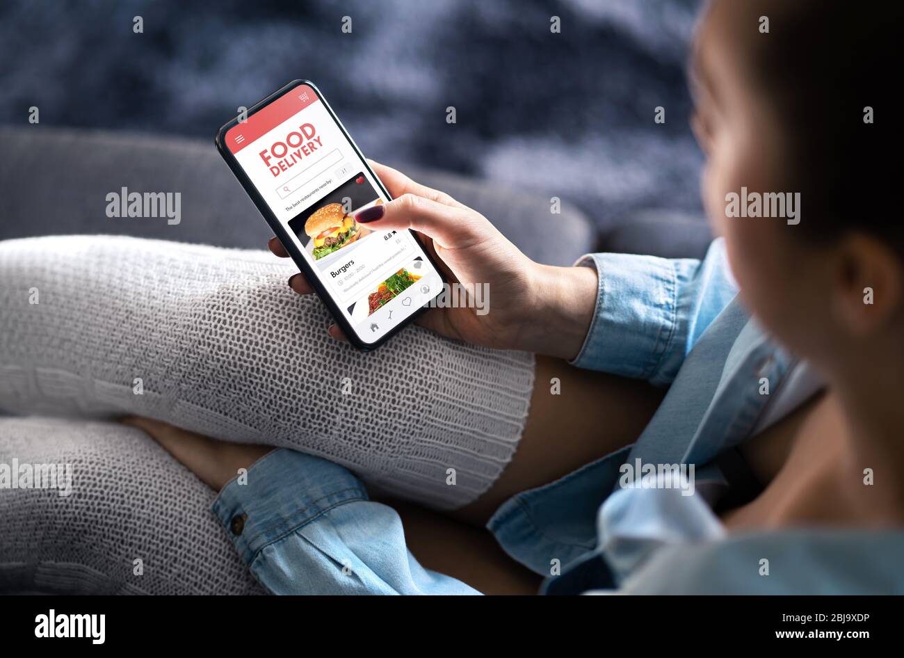 Food delivery app in mobile phone. Restaurant order online. Woman using smartphone to get take away lunch home delivered. Fast courier service. Stock Photo