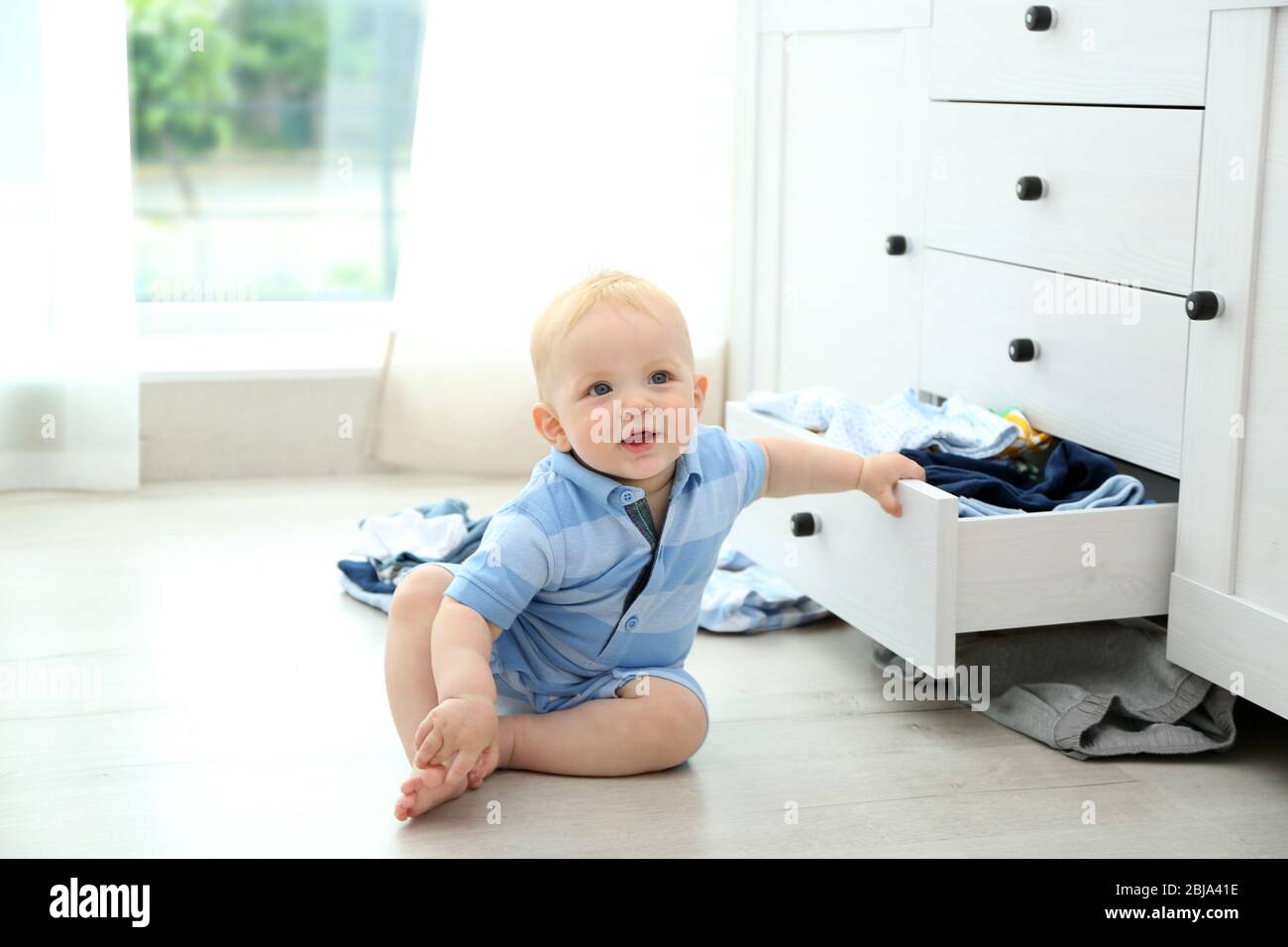 Baby throwing up clothes from wooden chest Stock Photo Alamy