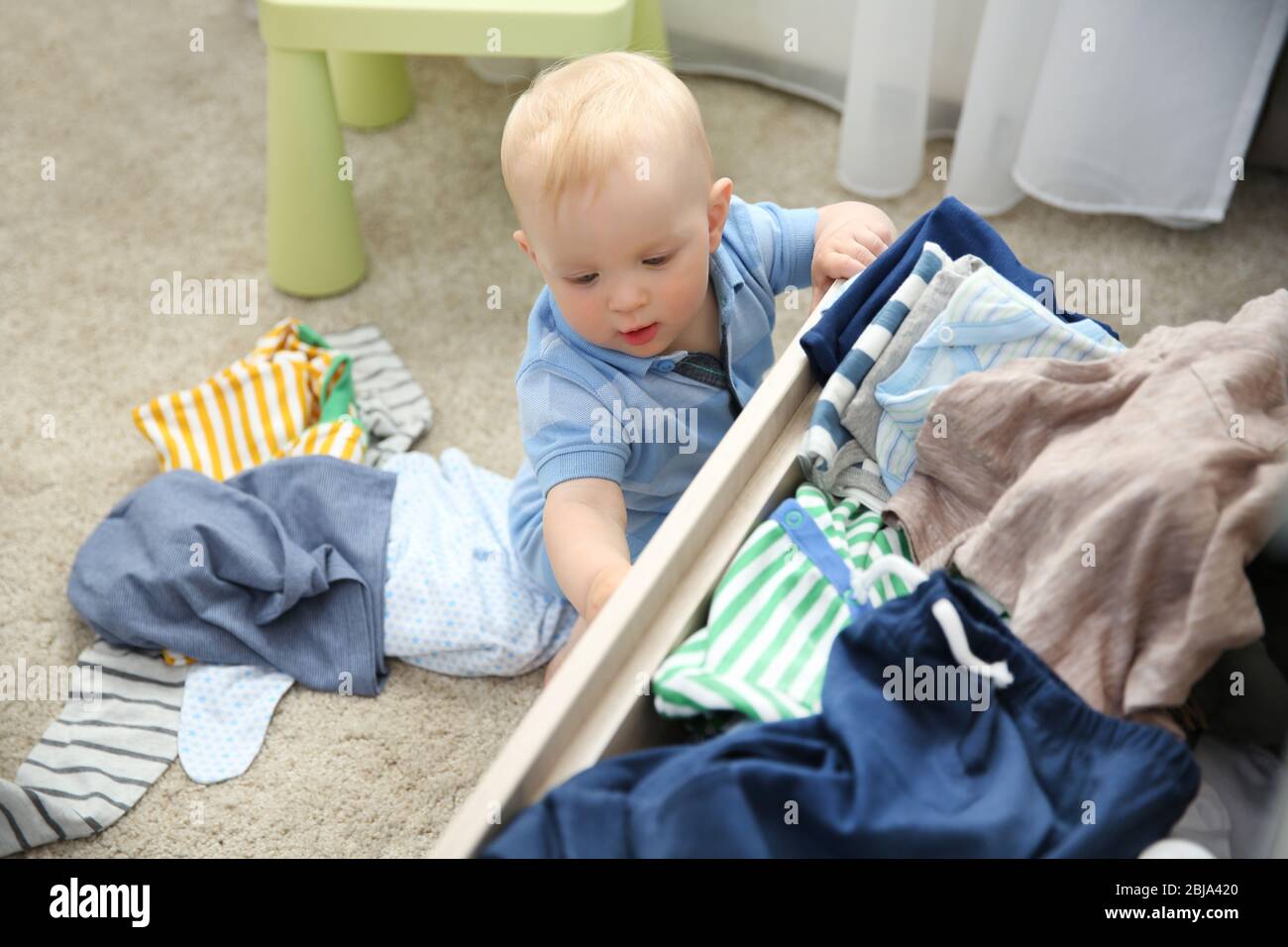 Baby throwing up clothes from wooden chest Stock Photo Alamy