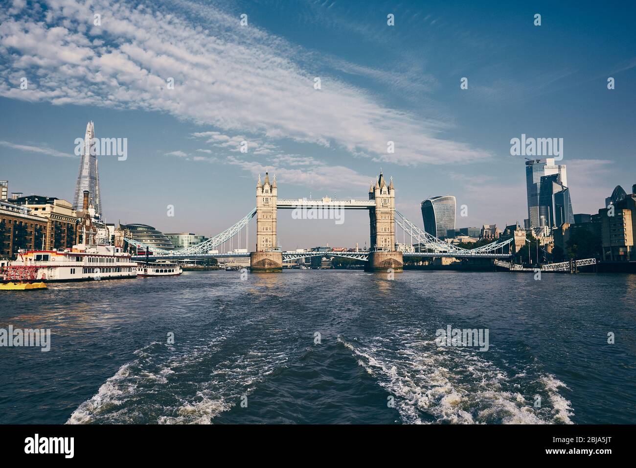 Tower Bridge in the middle of urban skyline. View from speedy boat on Thames River. London, United Kingdom. Stock Photo