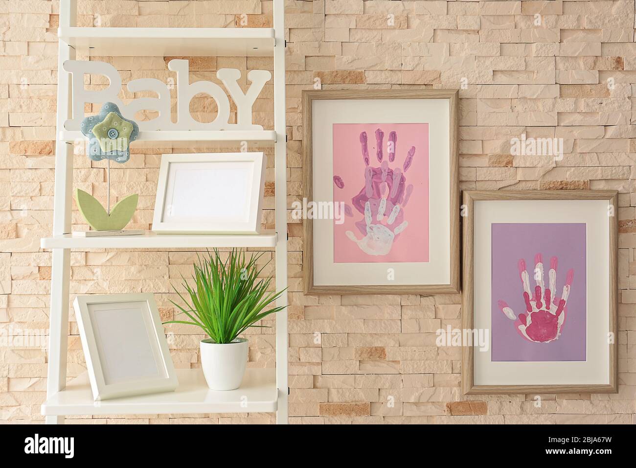 Family hand prints in frame hanging on brick wall Stock Photo
