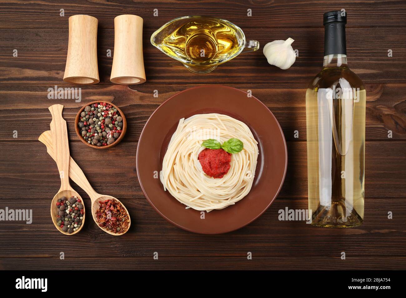 Composition of spaghetti in brown plate on wooden background Stock Photo