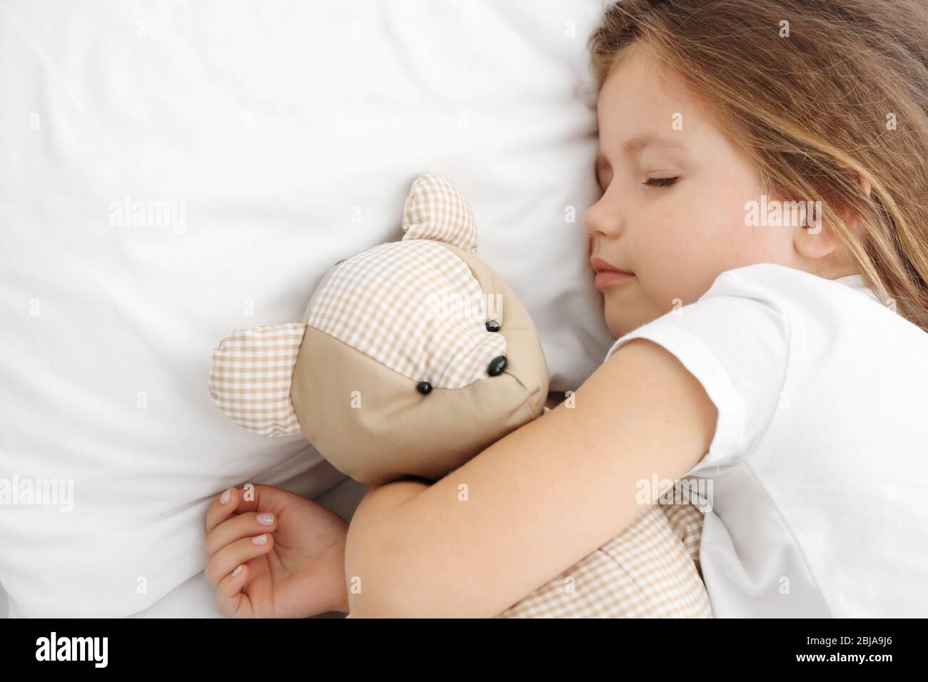 Cute little girl sleeping with teddy bear in bed Stock Photo - Alamy