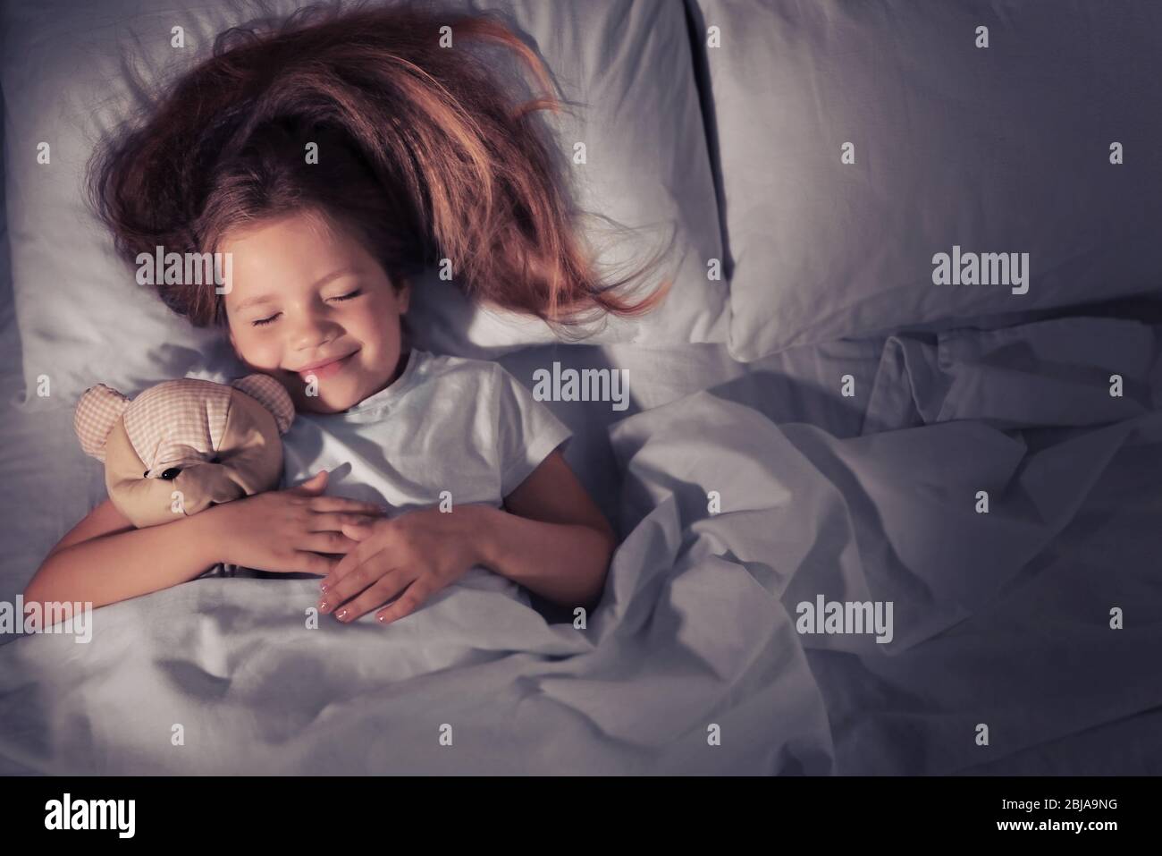Cute little girl sleeping with teddy bear in bed Stock Photo - Alamy