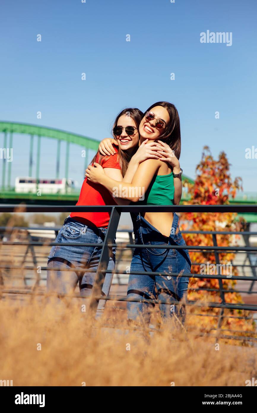 Two trendy young best female standing by the old bridge on a hot summer day Stock Photo