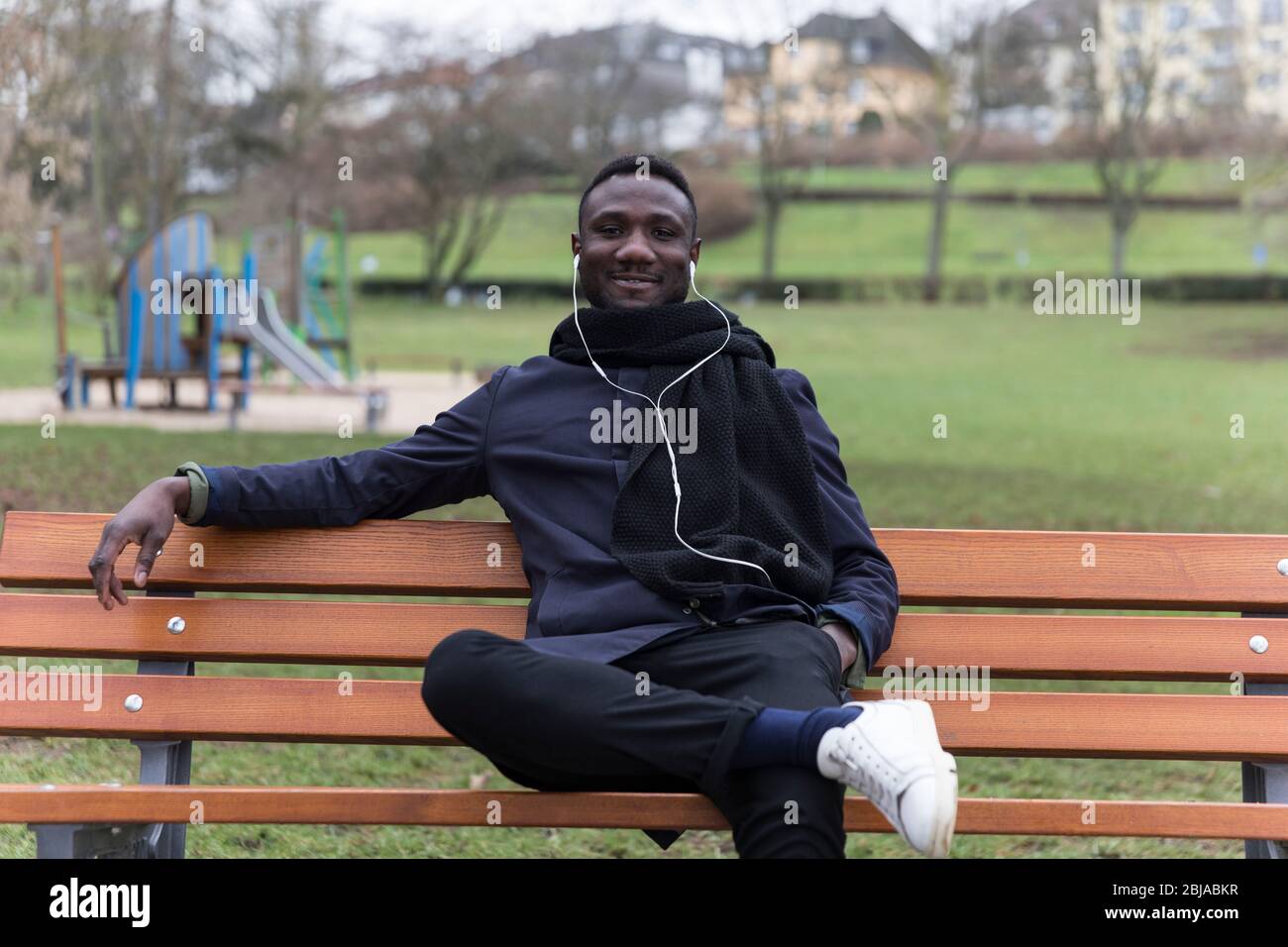 Young Black Man Leaning Back on Park Bench Confidently Stock Photo