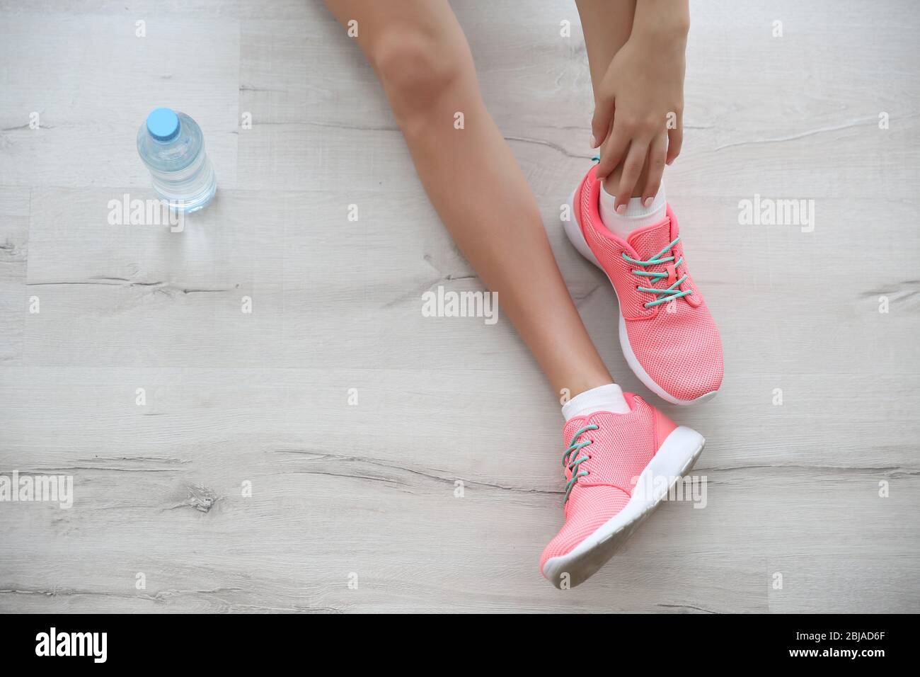 Woman wearing pink sneakers on wooden floor background Stock Photo - Alamy