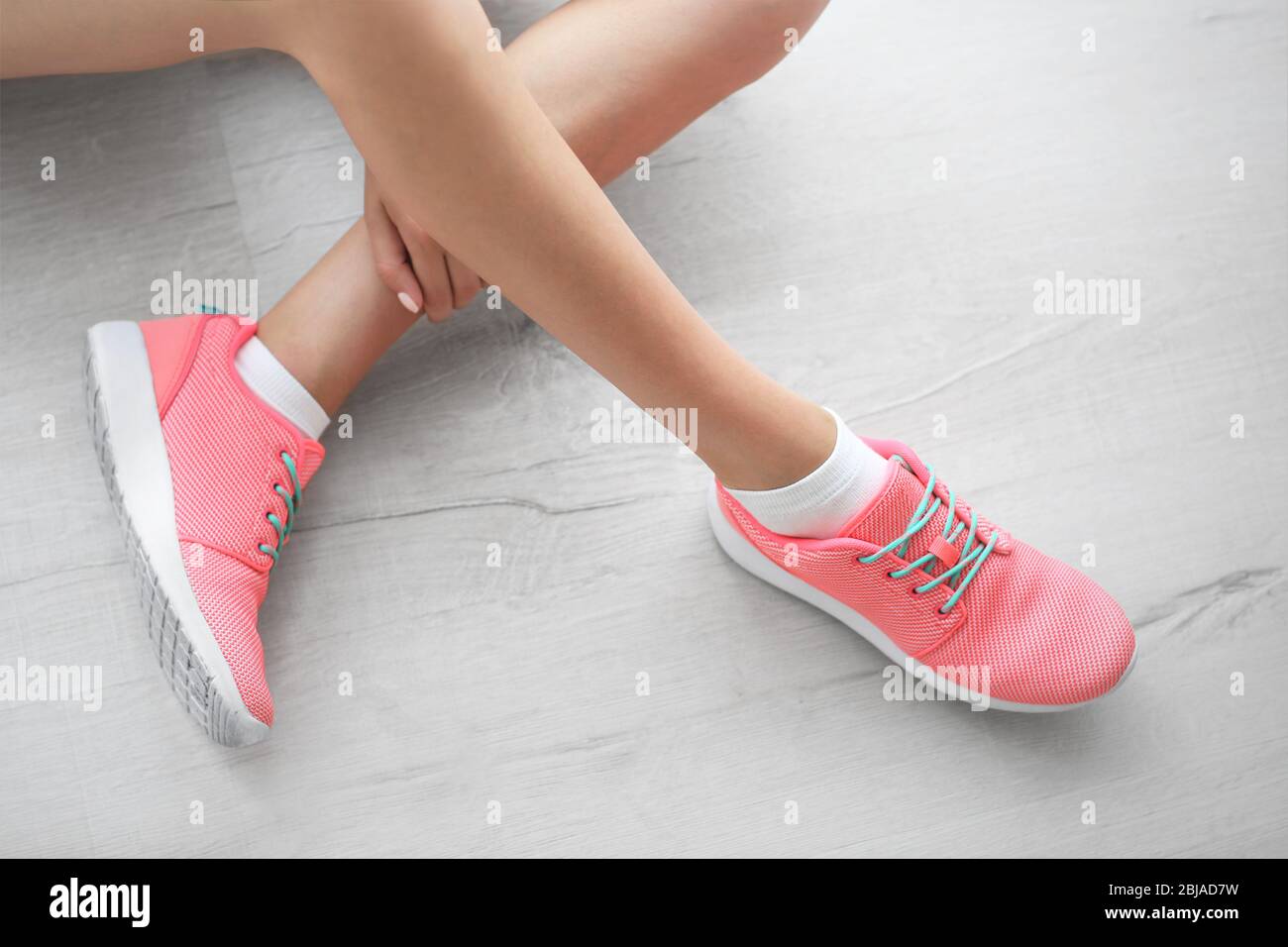 Woman wearing pink sneakers on wooden floor background Stock Photo - Alamy