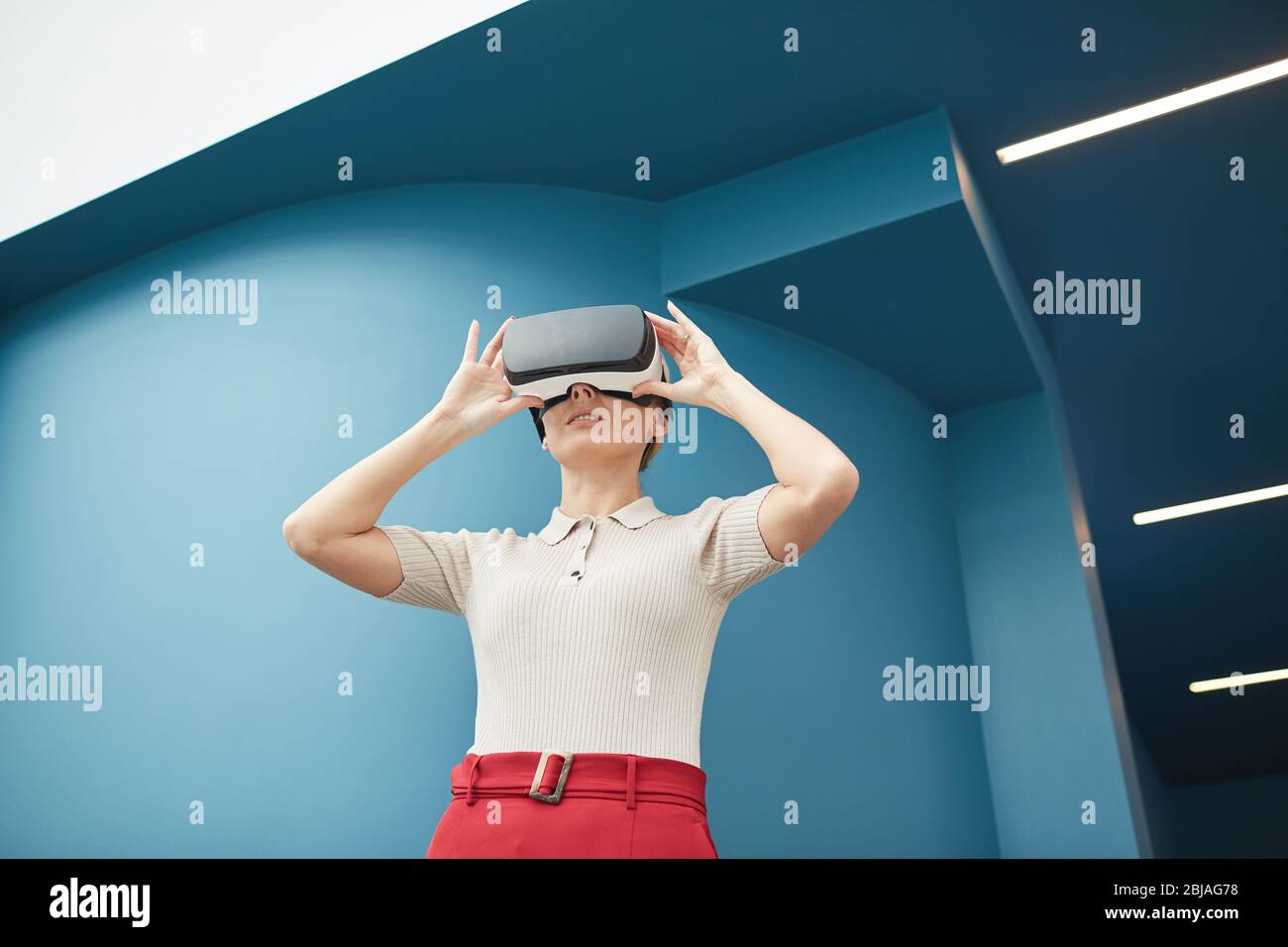 Young beautiful woman wearing virtual glasses watching some virtual reality outdoors Stock Photo