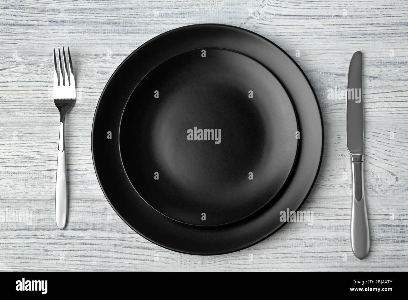 Empty plate, fork and knife on wooden background Stock Photo - Alamy