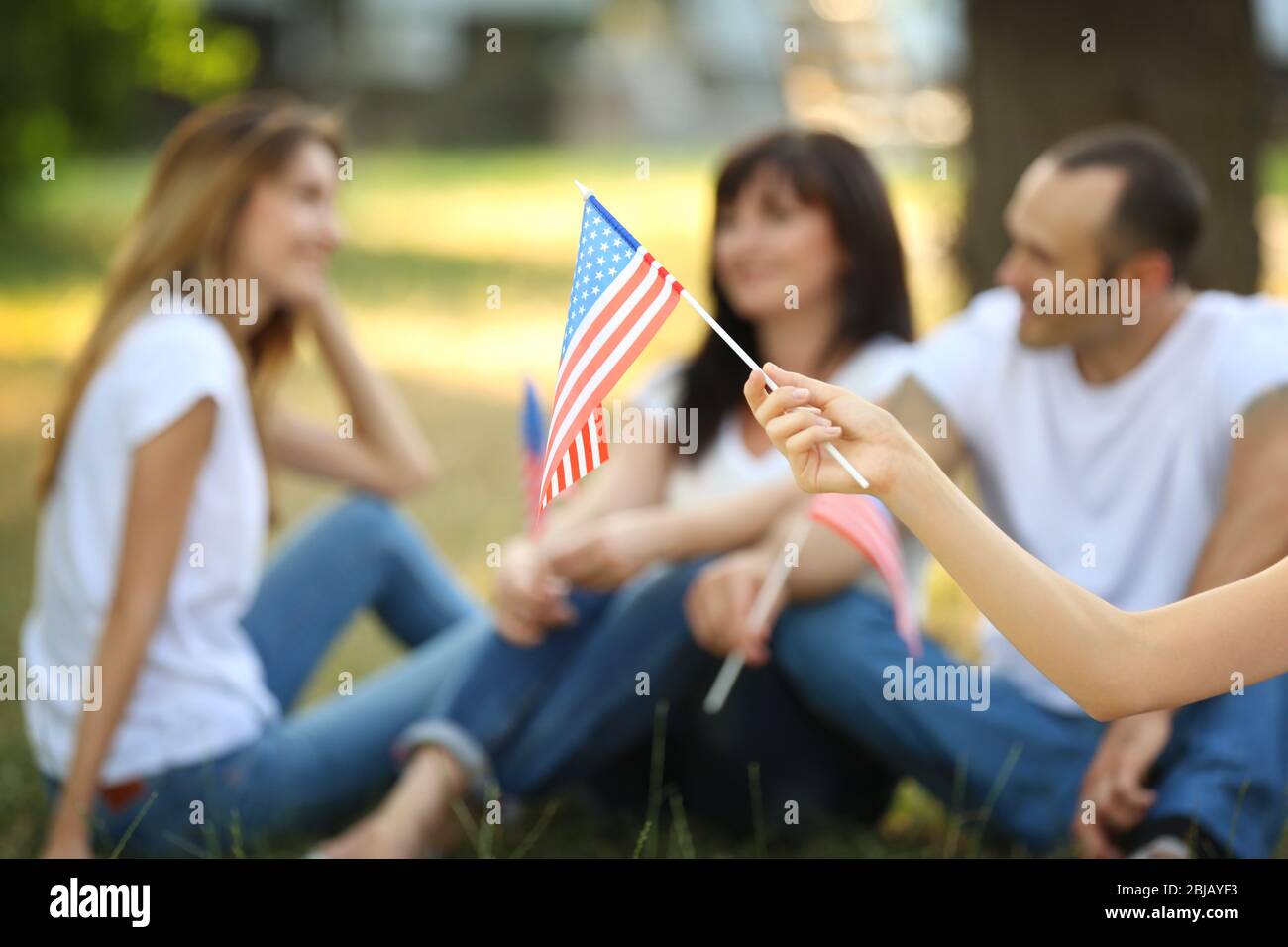 Female hand holding USA flag on blurred background Stock Photo