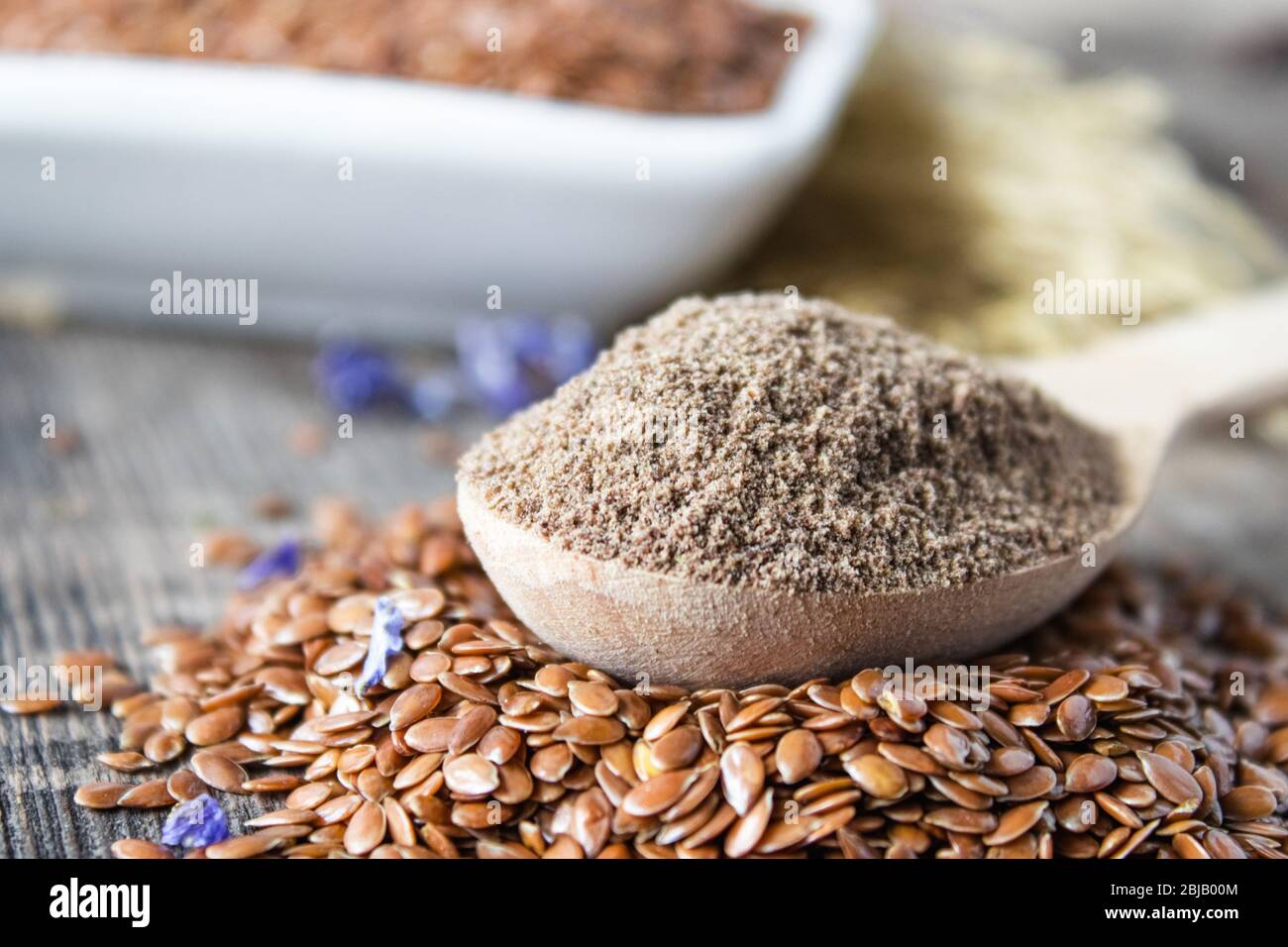 Crushed flax seed in a wooden spoon on a pile of flaxseed. Ground seed is used to prevent heart disease and being overweight. Stock Photo