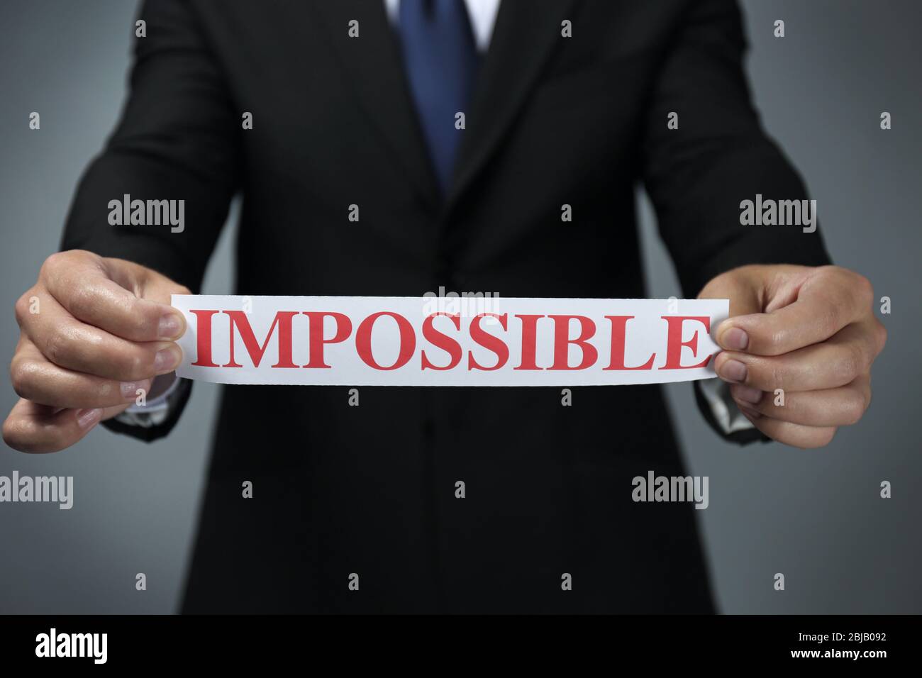 Businessman holding paper with impossible word Stock Photo - Alamy