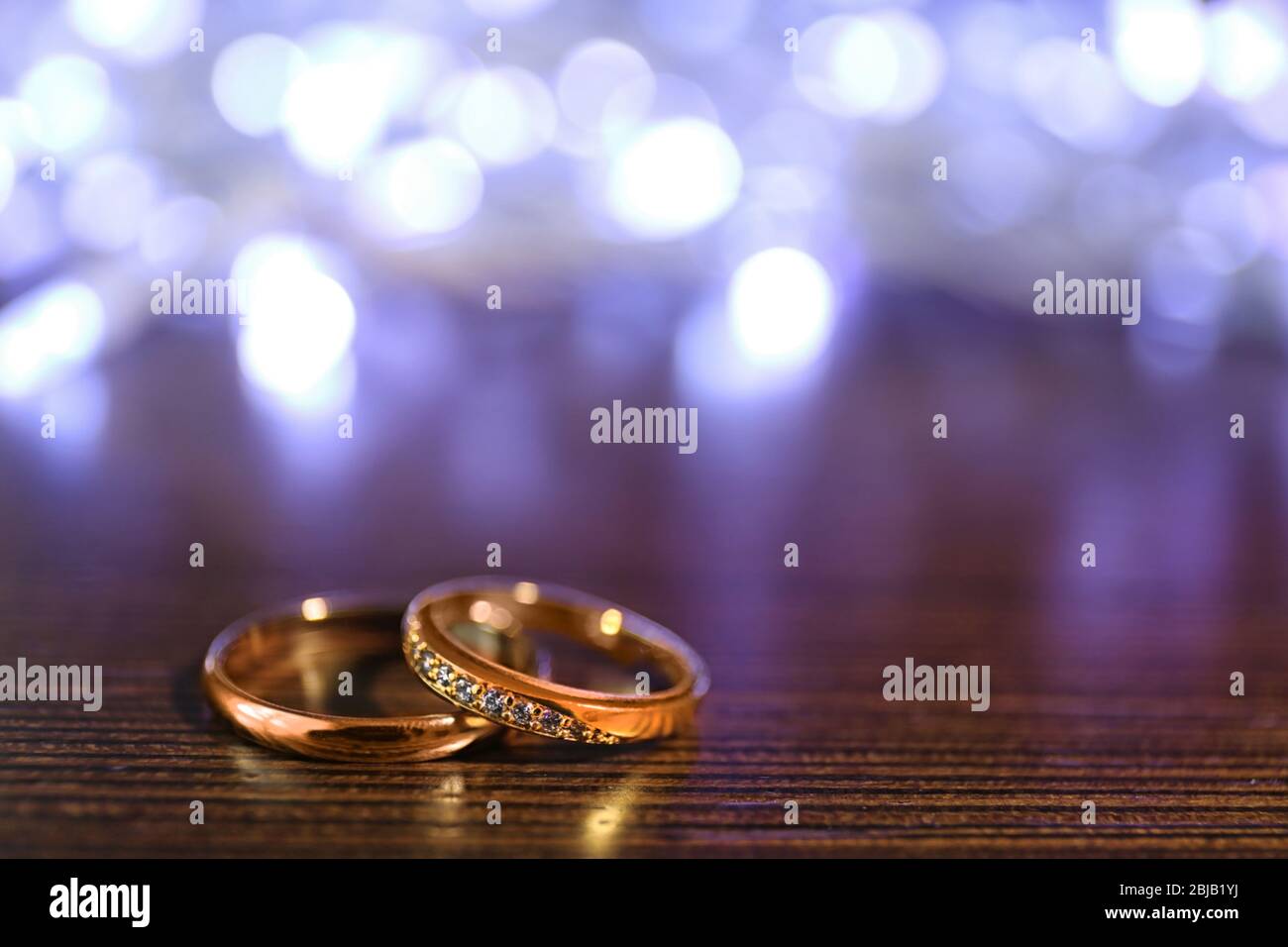 Wedding rings and blurred lights on wooden background Stock Photo - Alamy