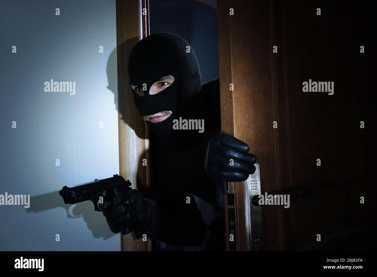 Armed thief entering a house Stock Photo