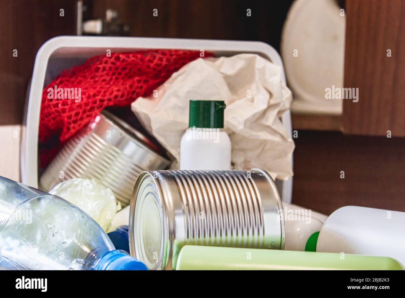 A plastic trash can with garbage lies on the floor near the kitchen ...