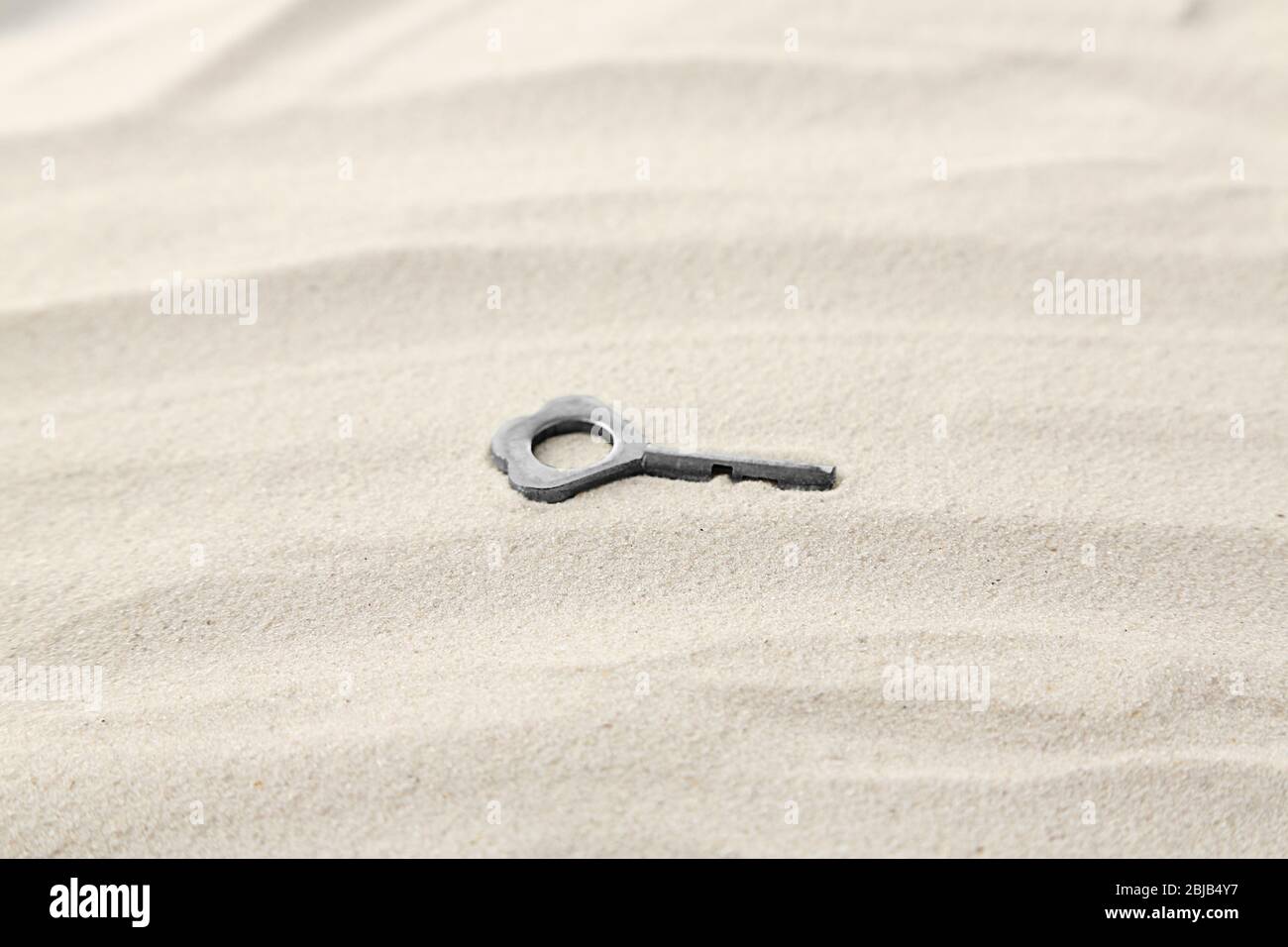 Vintage key on sand Stock Photo - Alamy