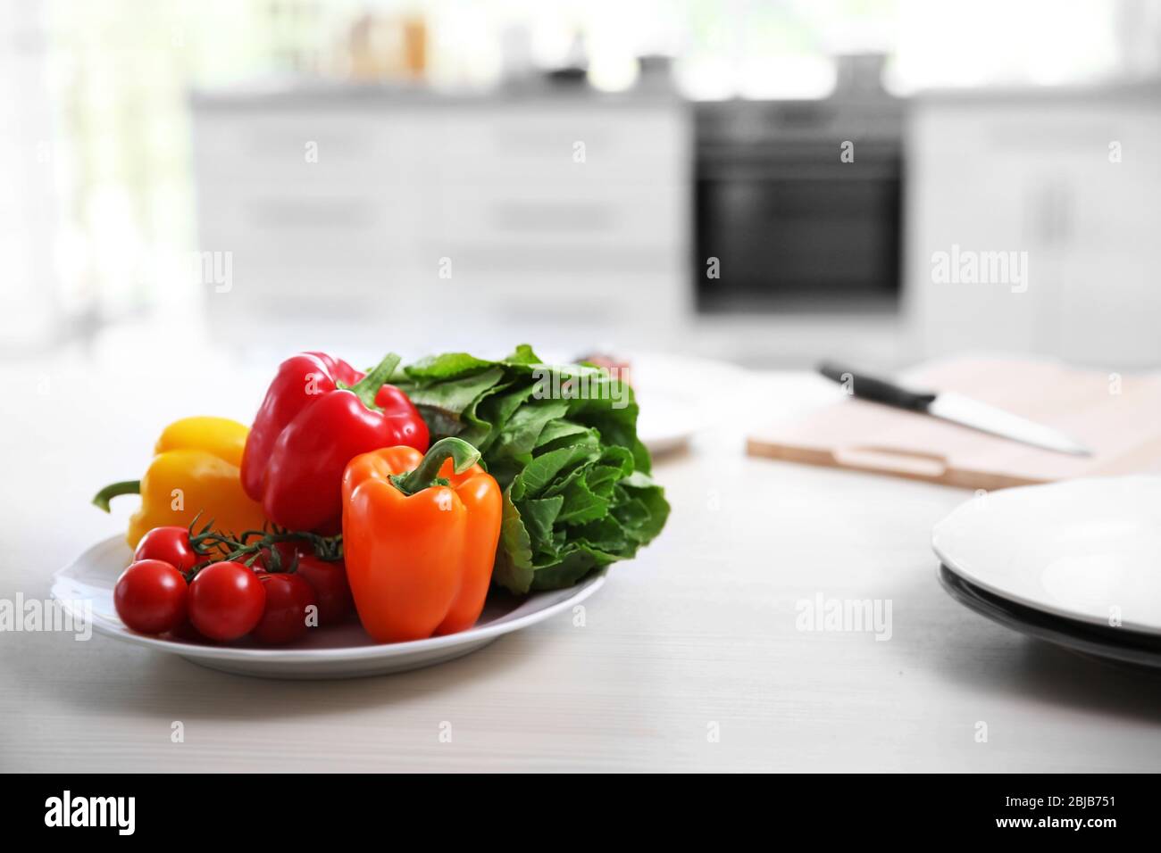 Plate with fresh vegetables on table, blurred kitchen background Stock  Photo - Alamy