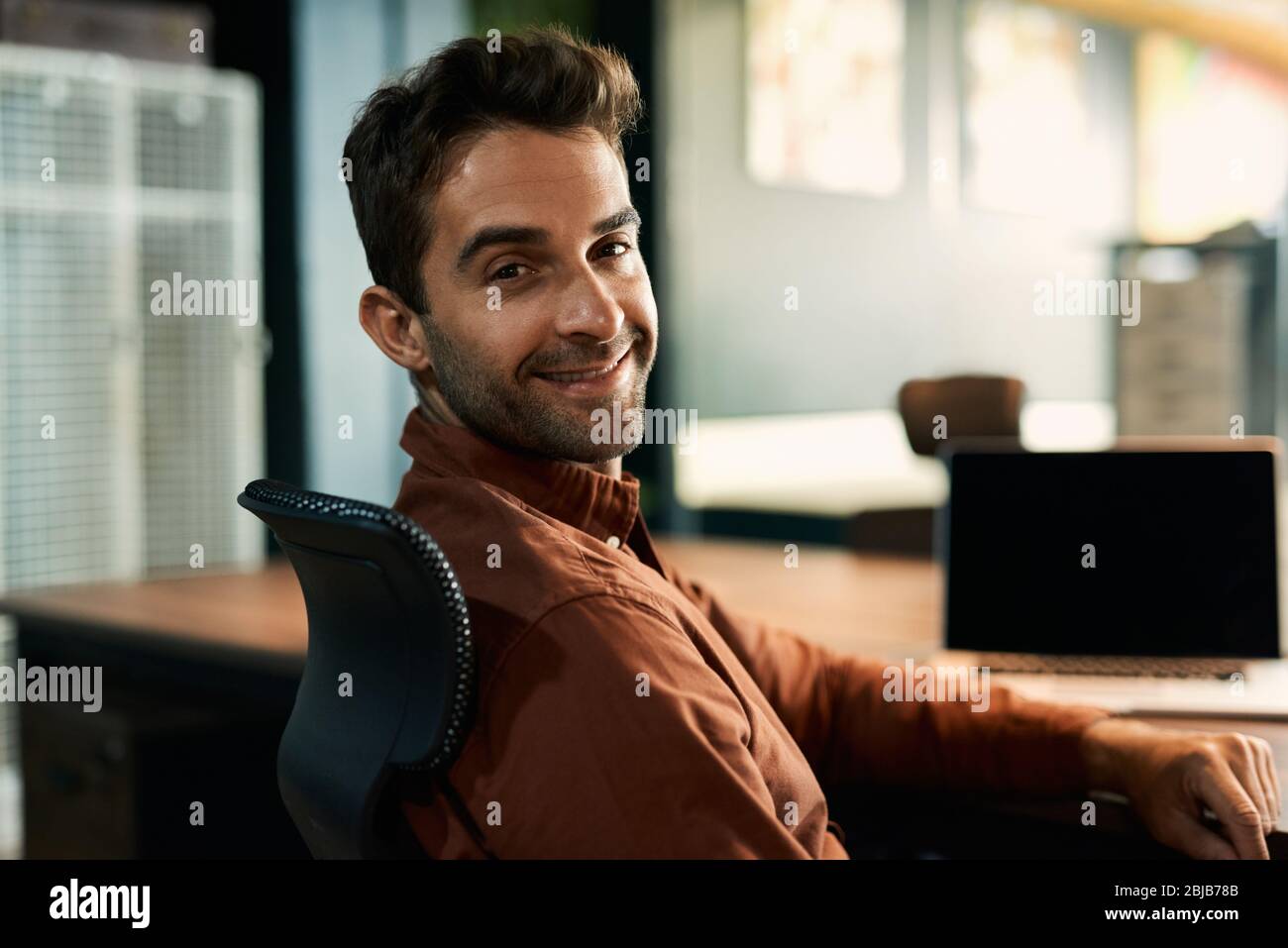 Businessman smiling while working late at his office desk Stock Photo