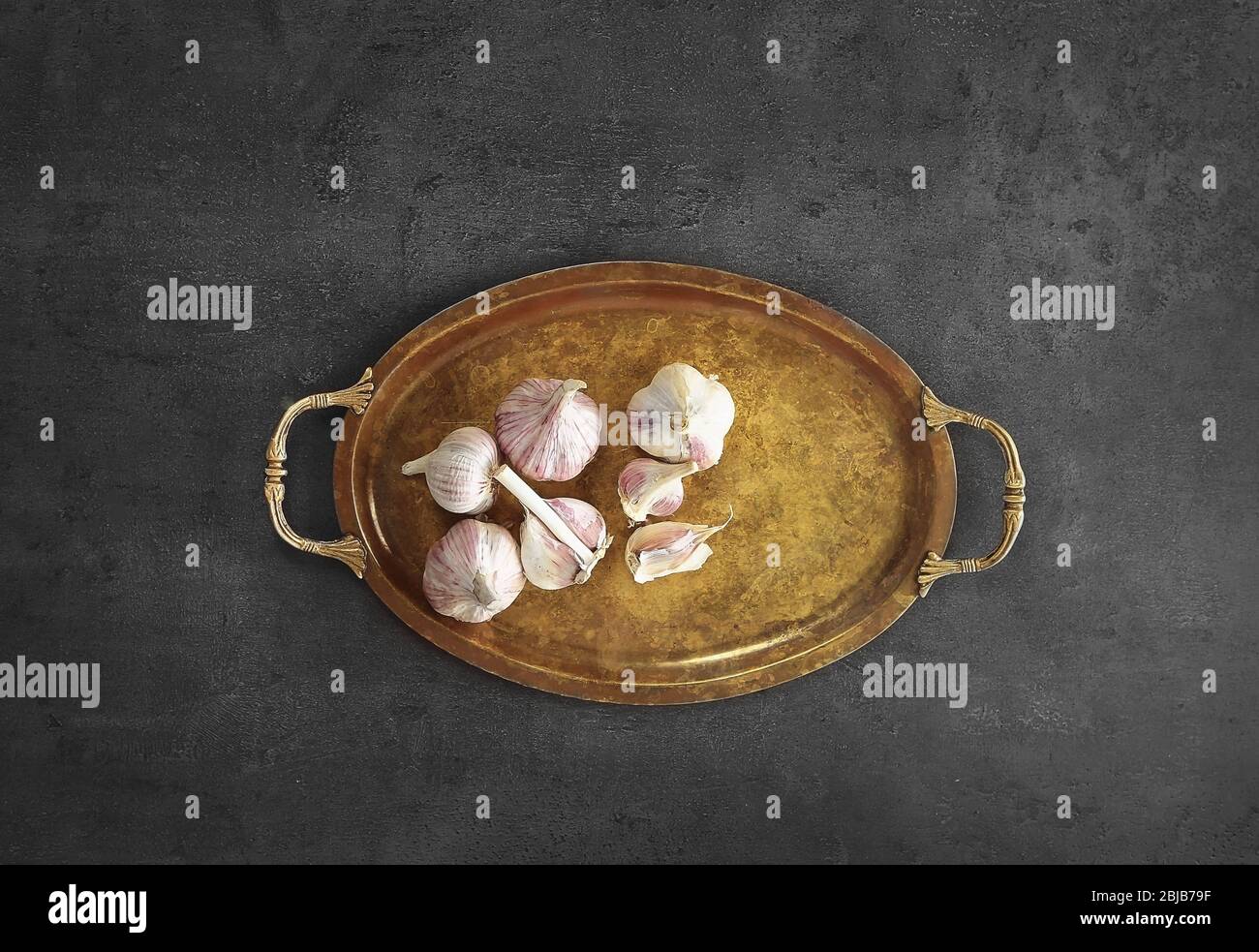 Metal tray with garlic on grey background Stock Photo - Alamy