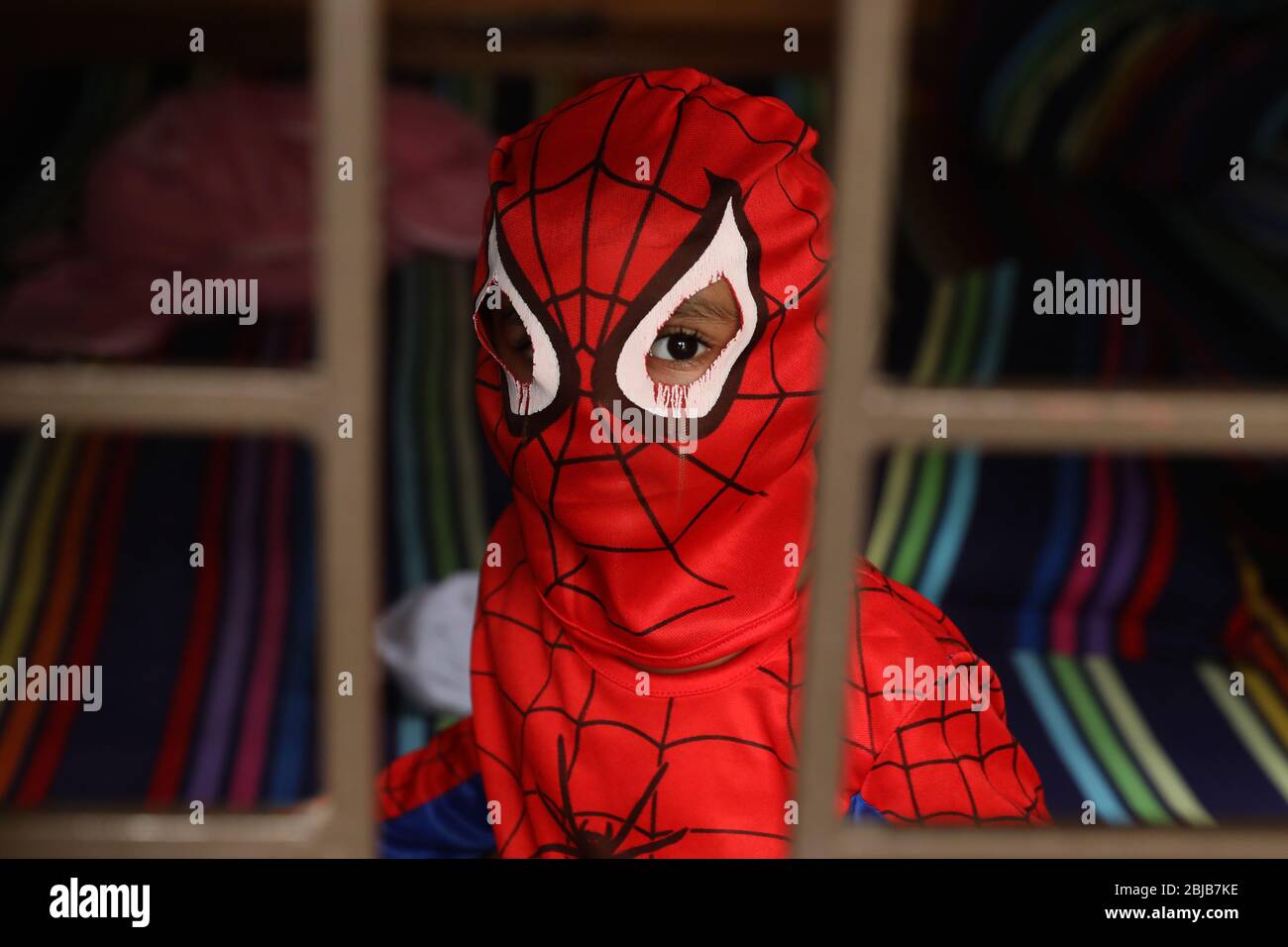 A child wearing a spider-man costume looks out of the window during the   71% of the children said they feel isolated and lonely due  to school closures and 91% of children
